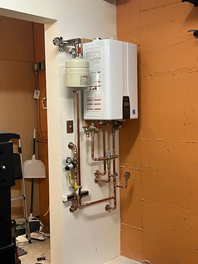Plumbing technician inspecting water heater connections in Clarence